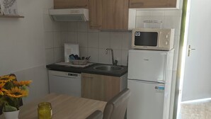 Eine kleine Küche mit Holzausstattung, einer Mikrowelle, einem Spülbecken und einem Kühlschrank.