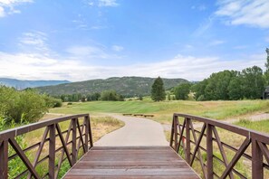 A wooden bridge leading to a golf course with a clear sky.