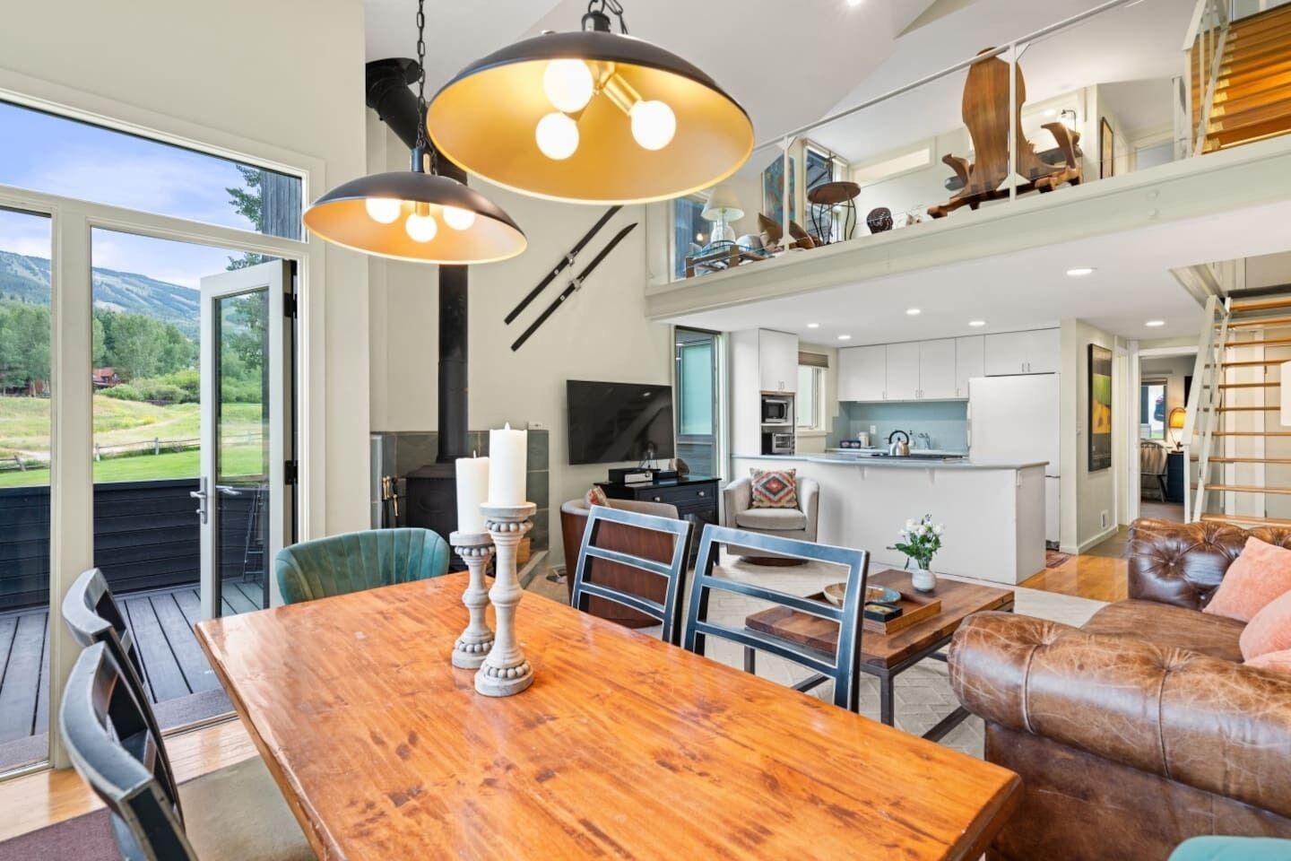 A modern interior with a wooden dining table, a leather sofa, and a kitchen area.