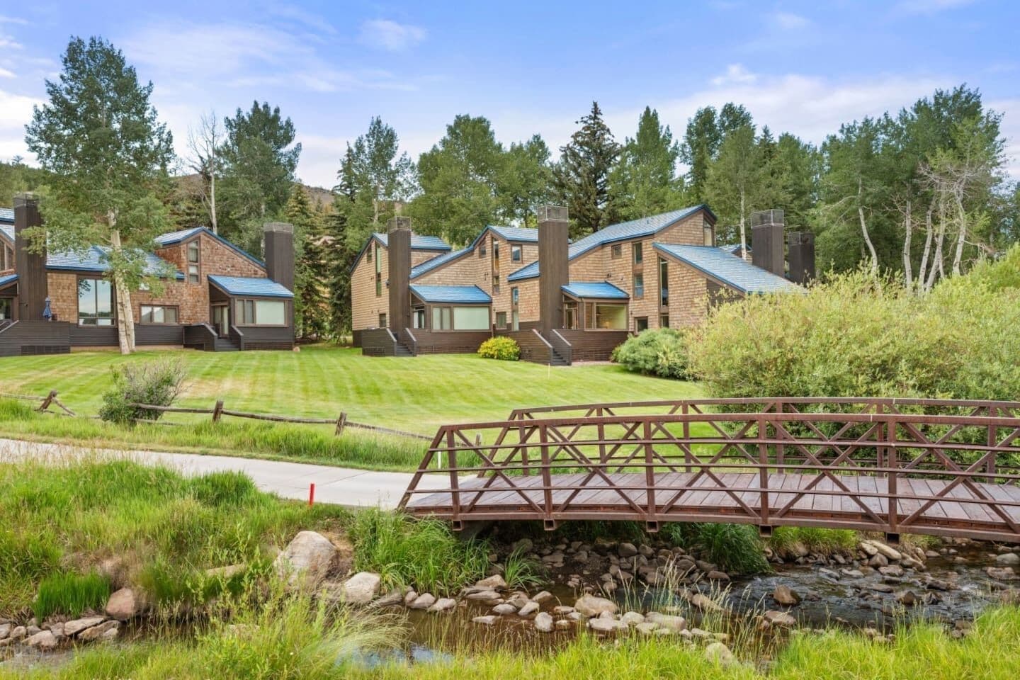 A residential area with multiple houses, a wooden bridge, and a stream.