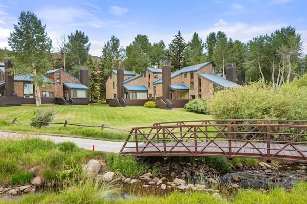 A residential area with multiple houses, a wooden bridge, and a stream.