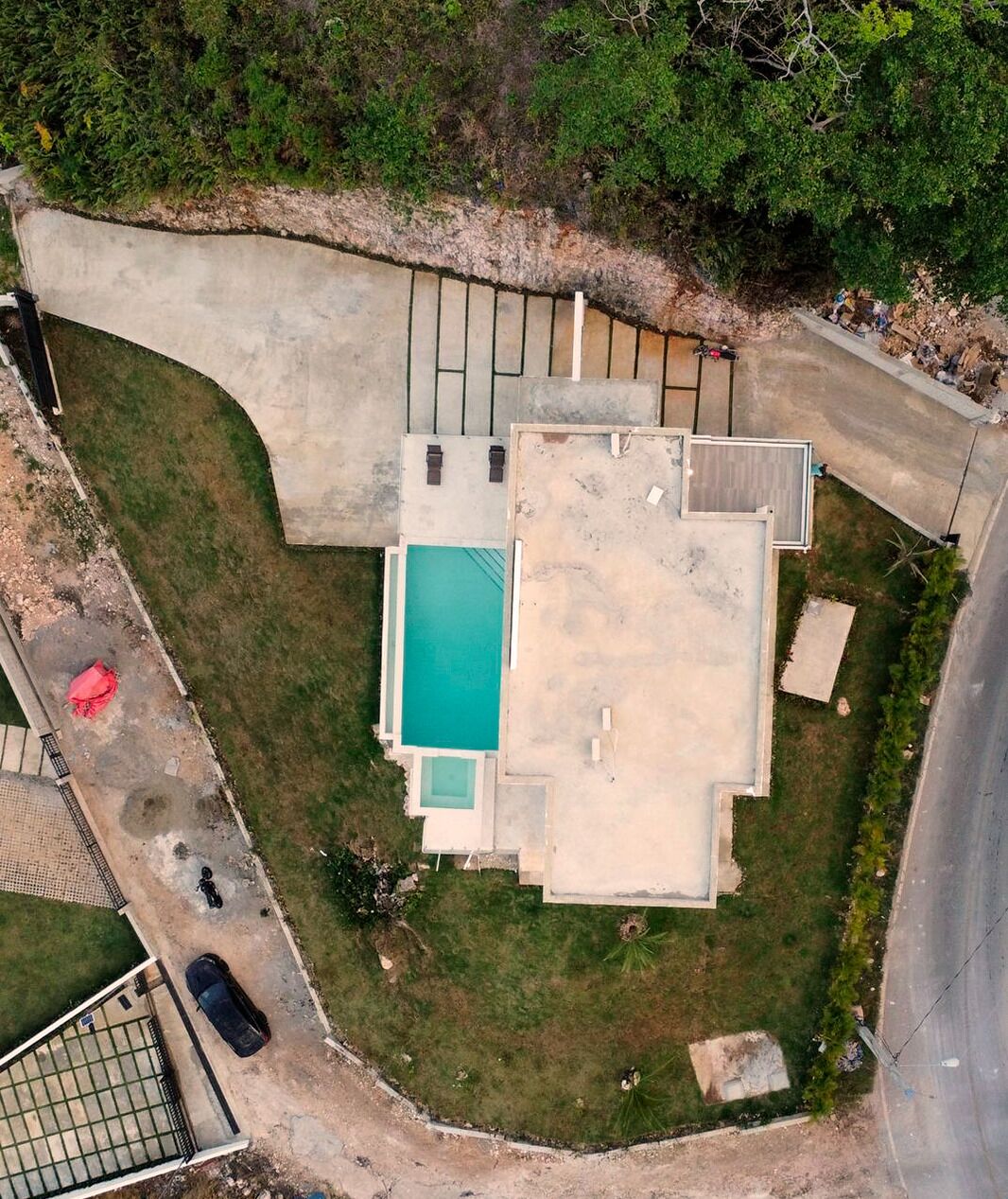 An aerial view of a property with a swimming pool, a covered patio, and a fenced yard.