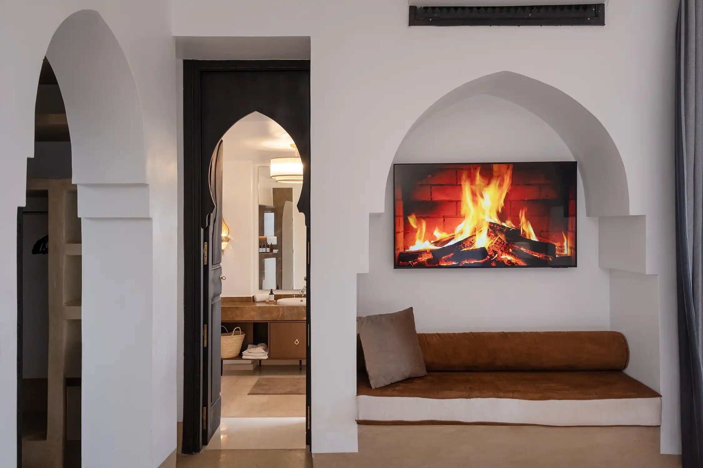 A modern living room with a fireplace, a sofa, and an arched doorway leading to another room.