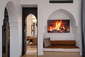 A modern living room with a fireplace, a sofa, and an arched doorway leading to another room.