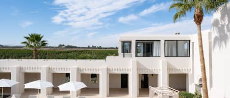 A modern villa with a rooftop pool area, including sun loungers and umbrellas.