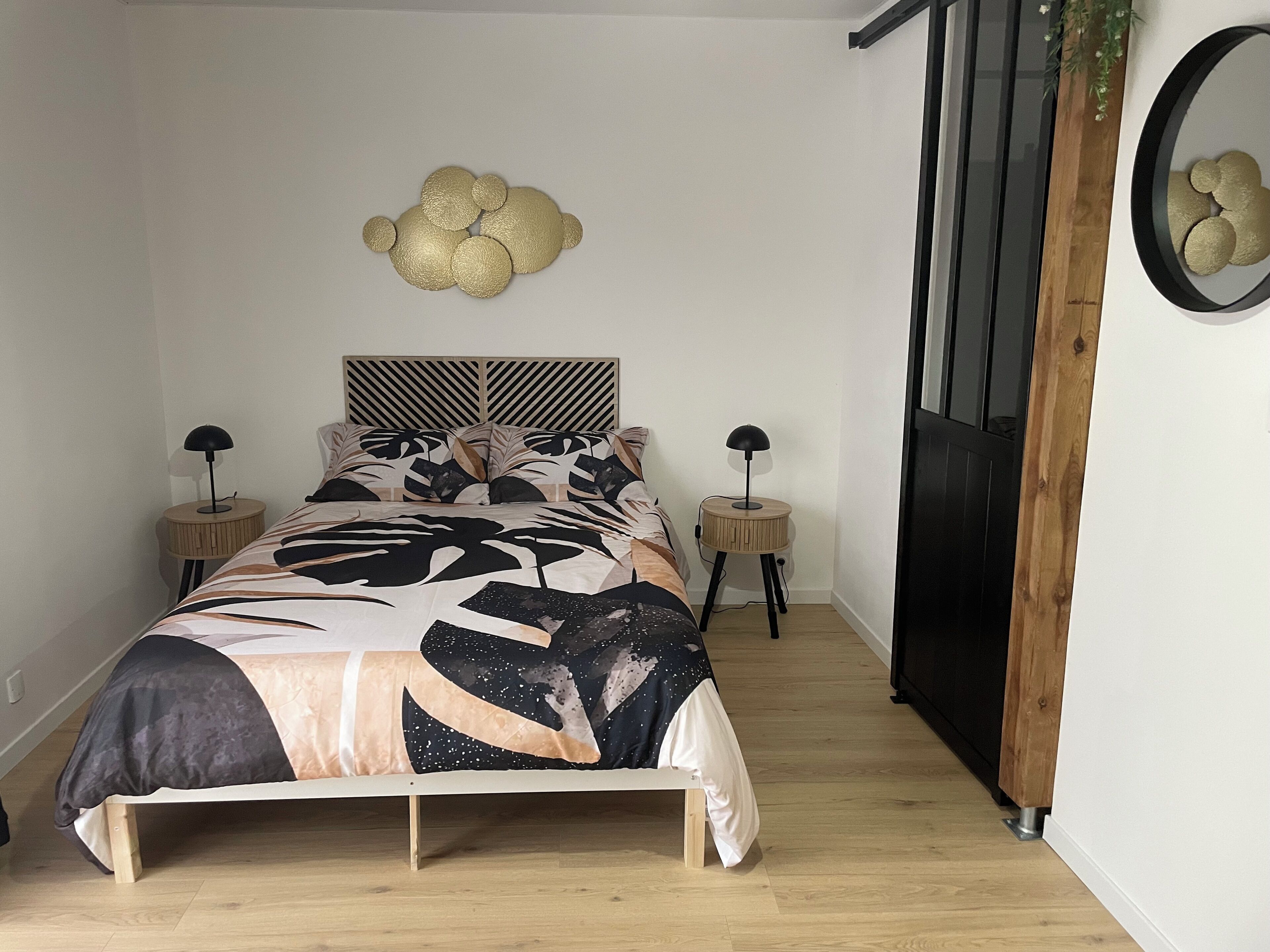 Une chambre à coucher comprenant un lit, des tables de chevet, un miroir fixé au mur et un élément décoratif mural.