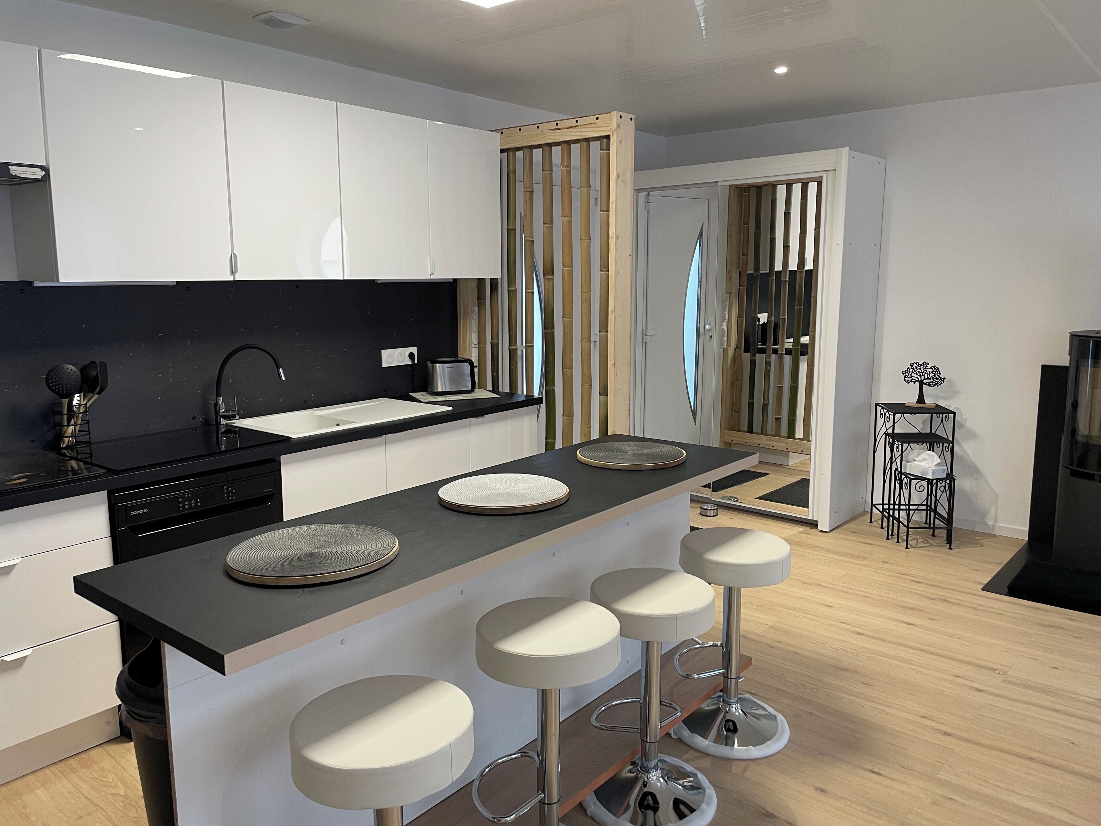 Una cocina moderna con una isla central, taburetes de bar, un tostador y un fregadero.