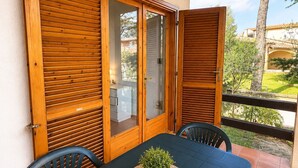 A balcony with a table and chairs, a potted plant, and a view of a residential area. - Casa Vacanze San Teodoro (San Teodoro)