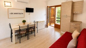 A modern living space with a dining area, a red sofa, and a kitchen area. - Casa Vacanze San Teodoro (San Teodoro)
