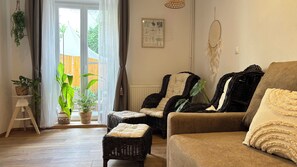 A living room with wicker furniture, a brown sofa, and a large window with curtains.