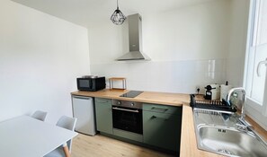 A compact kitchen with a dishwasher, oven, microwave, and a sink. - "Sauge de Sarrail" City Center Apartment (Saintes)