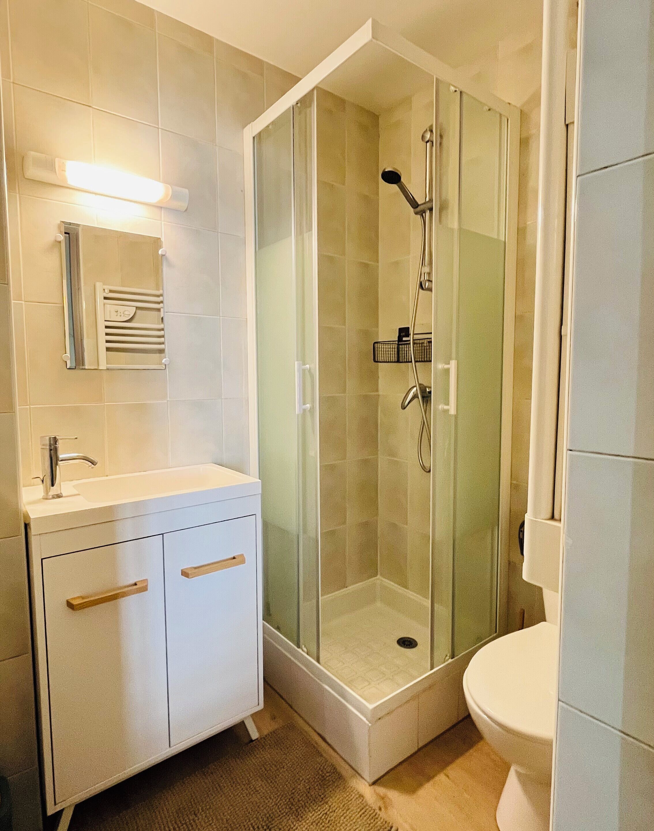 A bathroom with a glass-enclosed shower, a white sink, and a toilet.