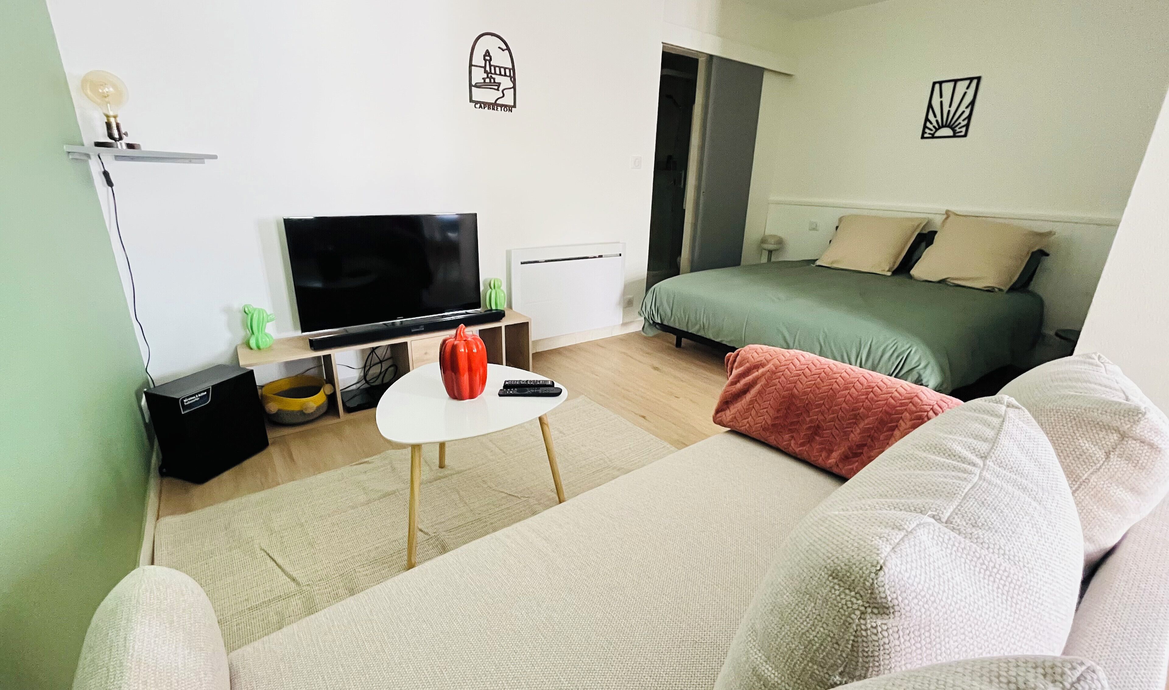Ein Hotelzimmer mit Bett, Fernseher, kleinem Tisch mit Vase und Fernbedienung sowie einer Sitzecke.