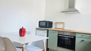 A compact kitchen with a microwave, a small oven, and a red pepper on the counter. - "Sauge de Sarrail" City Center Apartment (Saintes)