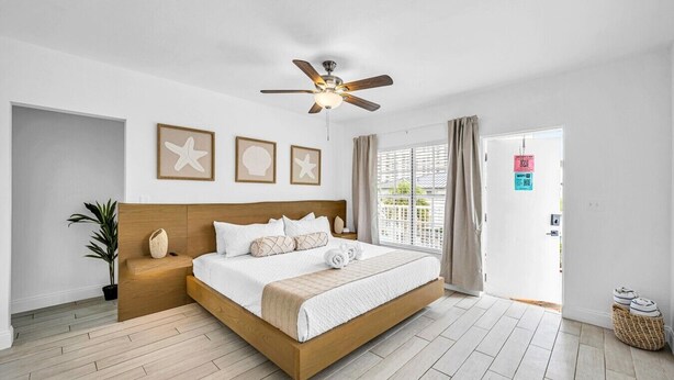 Hotelkamer met een bed, een plafondventilator, een kamerplant en uitzicht op buiten.