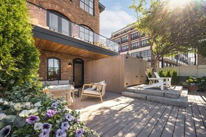 A wooden deck with outdoor seating, a brick building, and a clear sky. - Waterfront Luxury Home Downtown Traverse City (Traverse City)