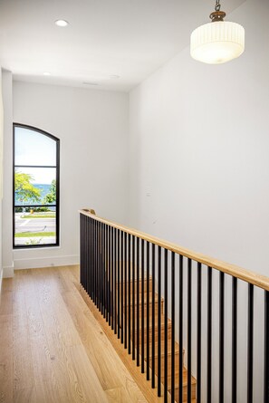 A staircase with wooden steps and black railings, leading to a landing with a view of the outdoors. - Waterfront Luxury Home Downtown Traverse City (Traverse City)