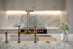 A kitchen with marble countertops, a gold faucet, and a vase with flowers. - Waterfront Luxury Home Downtown Traverse City (Traverse City)