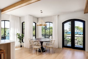 A dining area with a round table, six chairs, a hanging light fixture, and large windows with curtains. - Waterfront Luxury Home Downtown Traverse City (Traverse City)