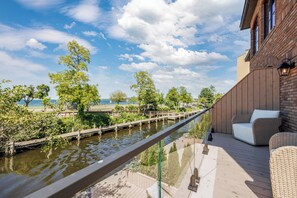 A deck with a view of a river, a wooden bridge, and a building with a brick facade. - Waterfront Luxury Home Downtown Traverse City (Traverse City)