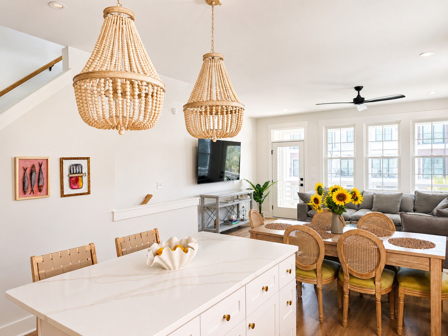 A spacious living area with a dining table, wicker chairs, a sofa, and a ceiling fan.