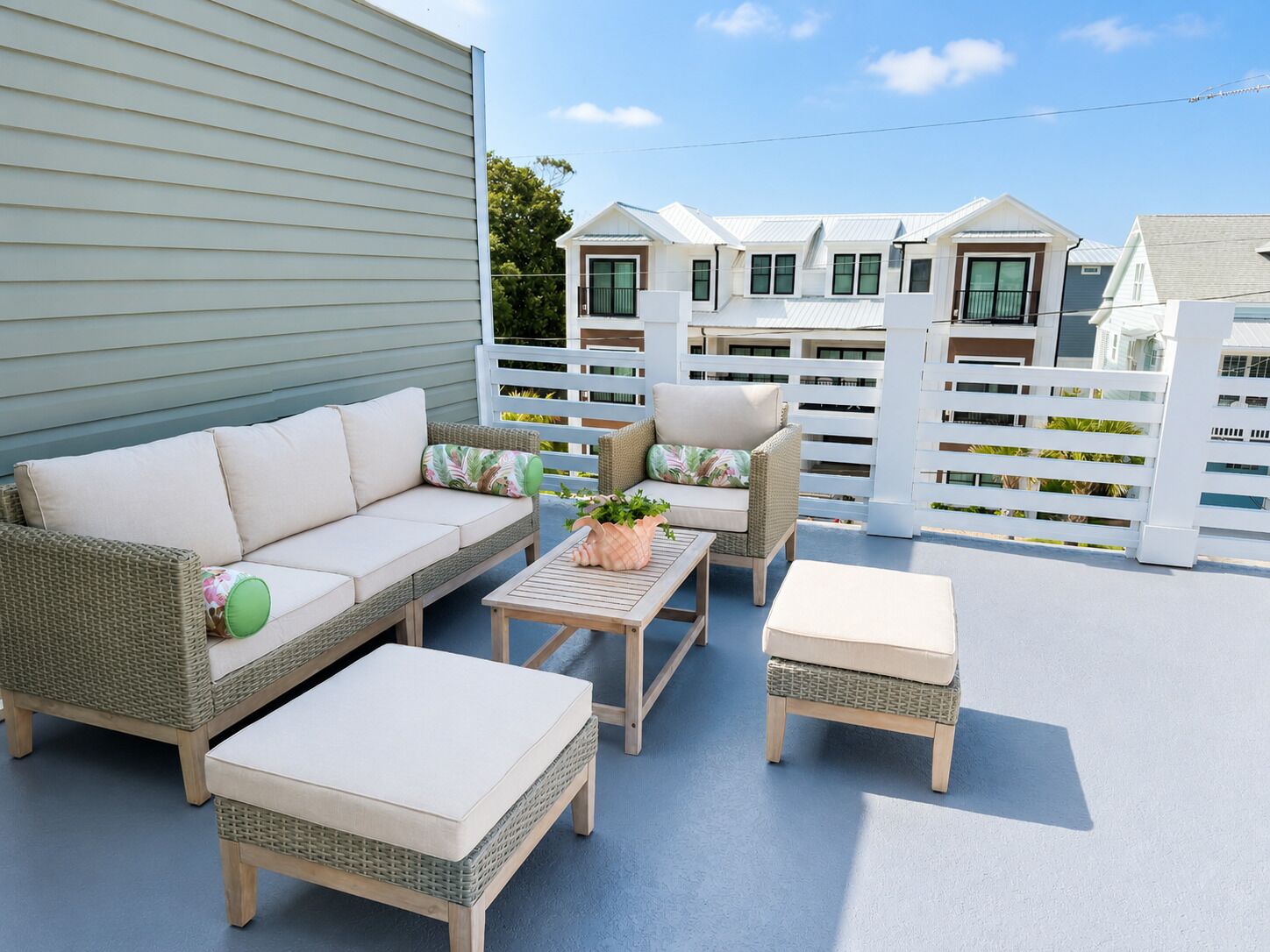 A covered outdoor seating area with a sofa, chairs, and tables.