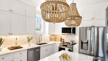 Una cocina moderna con armarios blancos, un refrigerador de acero inoxidable, un microondas y una isla grande con un bol de limones.
