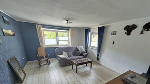 Una sala de estar con sofá, mesa de centro, sillón mecedora y televisor.