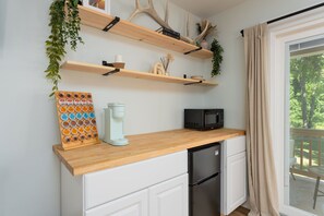 Eine Küche mit Holzböden, einer Kaffeemaschine, einer Mikrowelle und einem Kühlschrank.