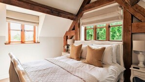 A bedroom with a bed, wooden beams, a window, and a nightstand. - Luxury Cotswolds Cottage for 7 (Tewkesbury)