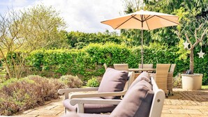 An outdoor seating area with wicker furniture and a large umbrella. - Luxury Cotswolds Cottage for 7 (Tewkesbury)