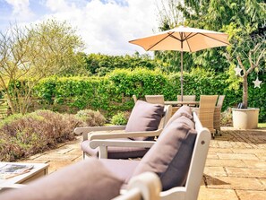 An outdoor seating area with wicker furniture and a large umbrella.