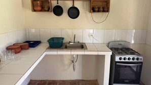 A compact kitchen with a gas stove, a sink, and a hanging pot rack. - Casa Verde Panajachel (Panajachel)