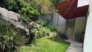 A small, enclosed outdoor area with a concrete wall, a grassy patch, and a red-roofed structure. - Casa Verde Panajachel (Panajachel)