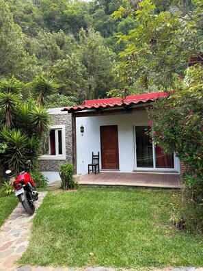 Una casita con techo rojo, pared de piedra y entrada empedrada.