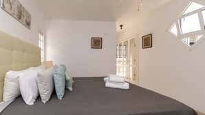 Een slaapkamer met een groot bed, een hoofdbord en twee ingelijste foto’s aan de muur.