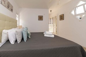 A bedroom with a large bed, a headboard, and two framed pictures on the wall. - Villa Aureo with private pool (La Caleta)