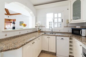 A kitchen with white cabinets, granite countertops, a dishwasher, a microwave, and a window with a view. - Villa Aureo with private pool (La Caleta)