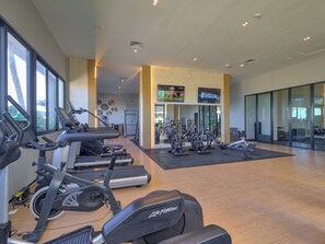 A spacious gym with various cardio machines, a television, and a reception area. - Luxury Oceanfront Condo | Marina Resort | 3BR | Pools | Sleeps 10 (Progreso)