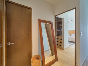 A room with a wooden door, a mirror, and an open closet with shelves. - Luxury Oceanfront Condo | Marina Resort | 3BR | Pools | Sleeps 10 (Progreso)