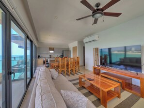 Ein modernes Wohnzimmer mit einer Couch, einem Holztisch, einem Fernseher und einem Deckenventilator.