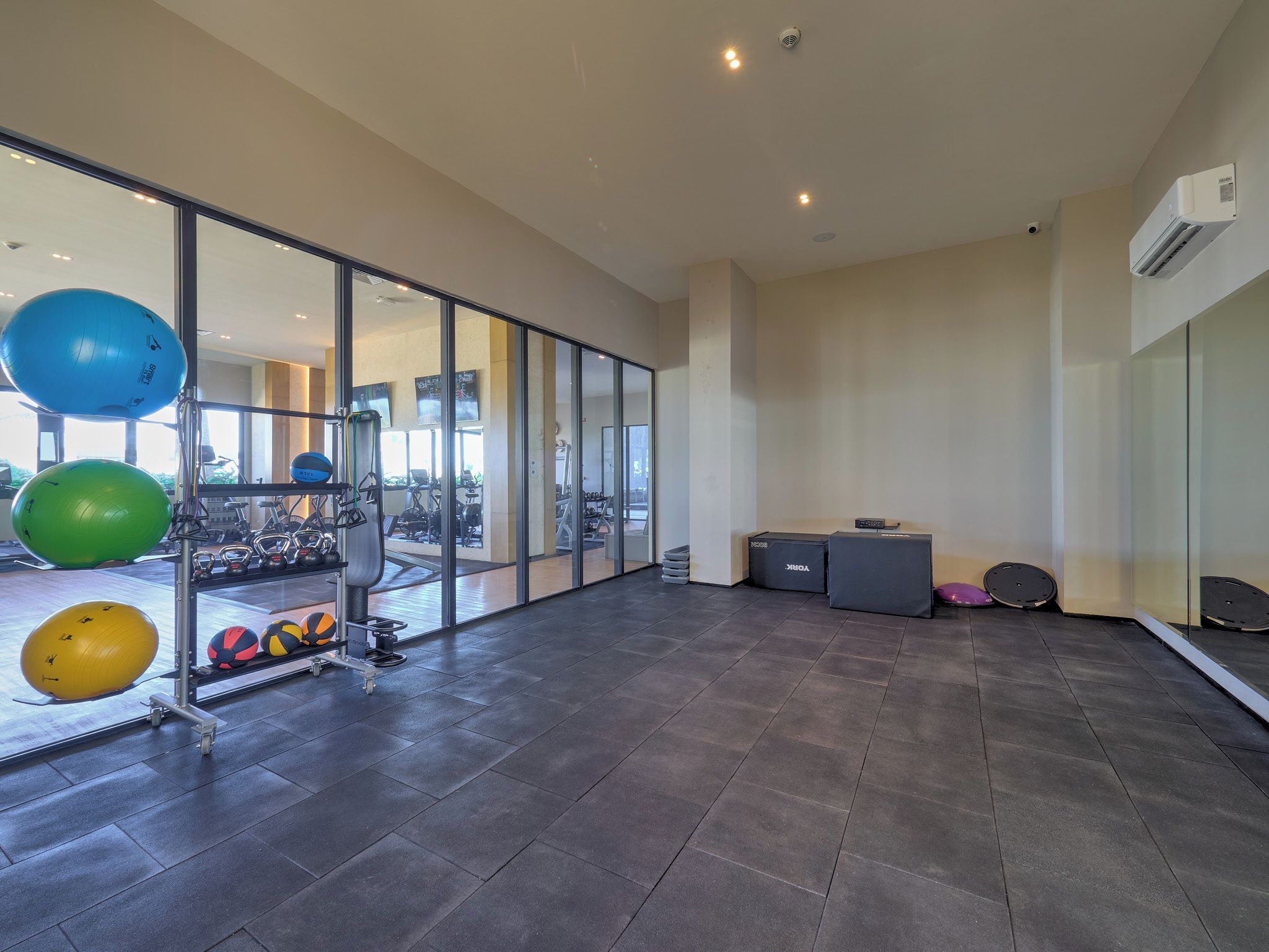 A spacious gym with exercise equipment, large windows, and a modern design.