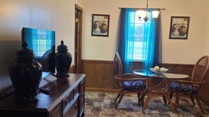 Un espace repas comprenant une table, des chaises, un lustre et des vases décoratifs.