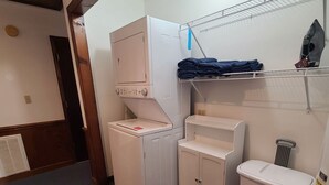 Une buanderie équipée d’un lave-linge, d’un sèche-linge et de paniers à linge empilés sur une étagère.