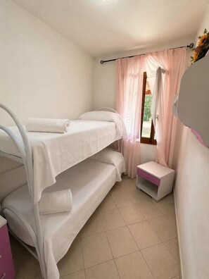 A room with bunk beds, a small table, and a window with curtains. - Beach Walk Apartments - San Teodoro (San Teodoro)
