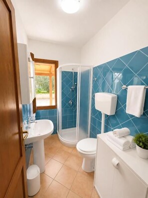 A bathroom with a shower, toilet, sink, and a window. - Beach Walk Apartments - San Teodoro (San Teodoro)