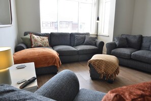 A living room with grey sofas, a white side table, and a lamp.