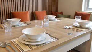 Una mesa de comedor servida con platos, cuencos, vasos y cubiertos.