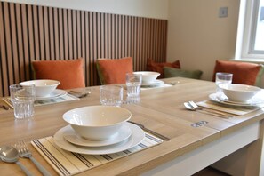 A dining table set with plates, bowls, glasses, and cutlery.