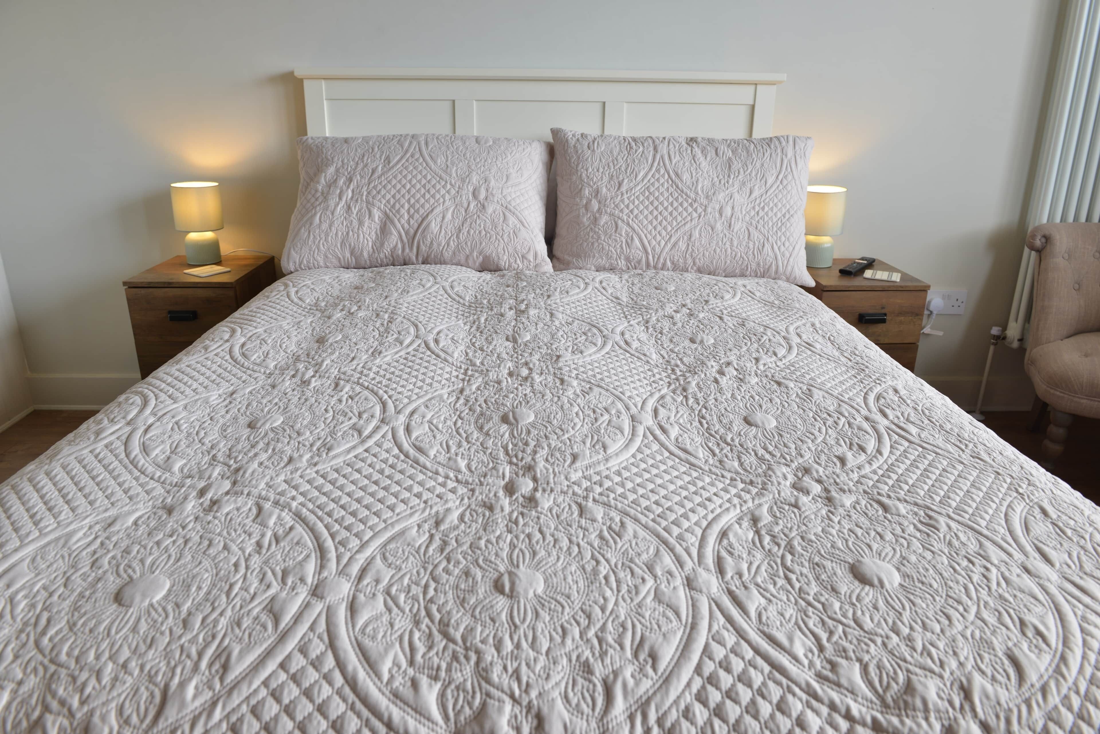 A bed with a quilted headboard and two bedside lamps.